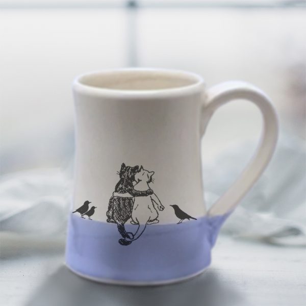Handmade coffee mug with a drawing of a black cat, a white cat and a few blackbirds quietly enjoying each other's company. Lavender accent color