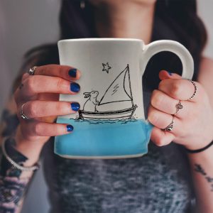 Handmade coffee mug with original illustration of a bunny sailing the high seas. Light blue accent color. Made by hedgehogs in the Blue Ridge Mountains.