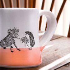 Just a sweet handmade mug with a roguish hedgehog offering a luscious carrot to a donkey princess. Coral accent color.