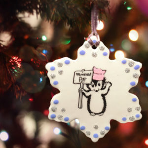Handmade ceramic ornament with drawing of hedgehog holding a feminist as fuck protest sign. Joy to the girls.