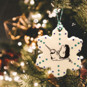 Handmade ceramic ornament with drawing of hedgehog riding a narwhal. Joyeux Narwhal to you!
