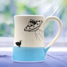 Handmade mug with a typical Darn Pottery illustration of a UFO and a dodo. Blue accent color.