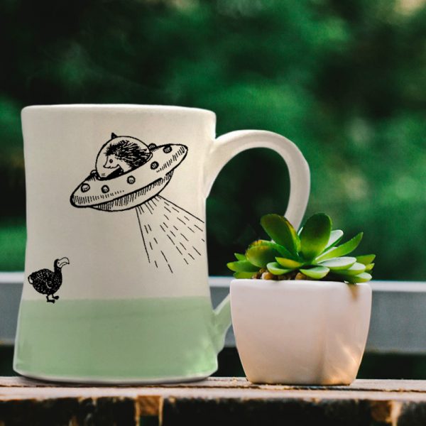 Handmade mug with a typical Darn Pottery illustration of a UFO and a dodo. Green accent color.