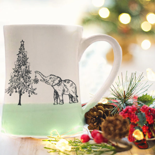 Handmade coffee mug with a drawing of either a very short elephant or a really tall christmas tree. Green accent color.