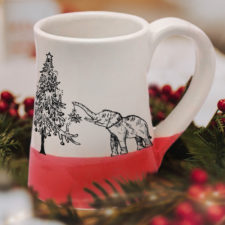 Handmade coffee mug with a drawing of either a very short elephant or a really tall christmas tree. Red accent color.