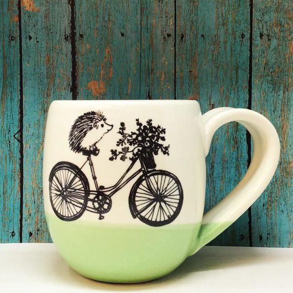 Handmade ceramic cocoa mug with drawing of hedgehog on a bike