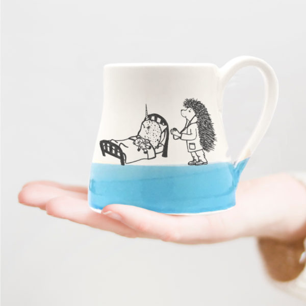 Handmade wheelthrown mug with drawing of a doctor hedgehog taking care of an ill narwhal
