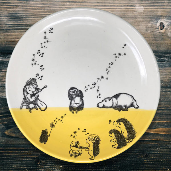 dinner plate with drawing of a manatee, a sloth, a hippo and a family of hedgehogs singing together