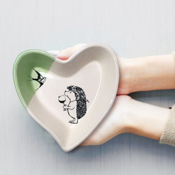 Handmade ceramic heart-shaped dish with drawing of a girl hedgehog with wine. Green accent color