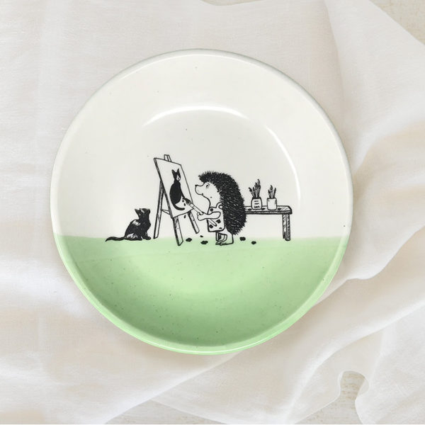 green salad plate with drawing of an artist hedgehog painting a cat