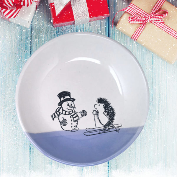 Handmade salad plate with a drawing of a hedgehog on skis greeting a well-dressed snowman. Lavender accent color