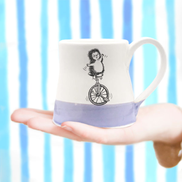 small mug with drawing of a hedgehog on a unicycle