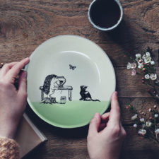 Handmade ceramic plate with drawing of a hedgehog painting a kitten on a pot. Green accent color