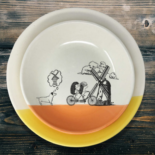 Handmade ceramic plate with drawing of hedgehogs on bikes, a windmill, and dog dreaming of peeing on it. Coral accent color