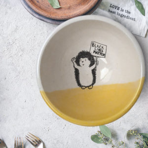 Handmade ceramic soup bowl with a drawing of a hedgehog holding a Black Lives Matter resistance sign. Gold accent color.