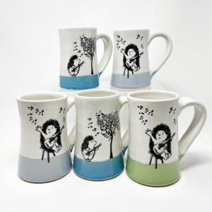 five handmade ceramic mugs with drawings of hedgehogs playing guitar and ukelele