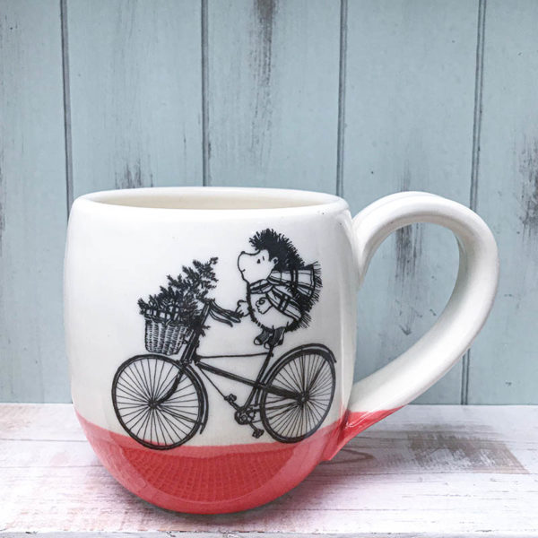 Cocoa mug with hedgehog on bike delivering christmas tree
