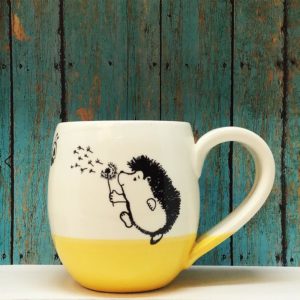Handmade ceramic cocoa mug with drawing of hedgehog blowing on a dandelion