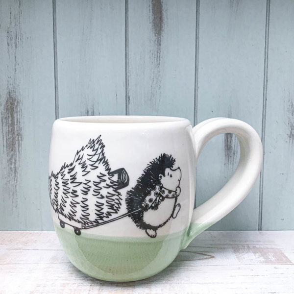 Cocoa mug with hedgehog dragging a fresh christmas tree from the forest