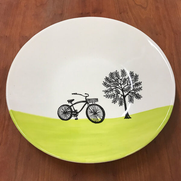 Handmade ceramic dinner plate with a black and white drawing of a bike near a tree