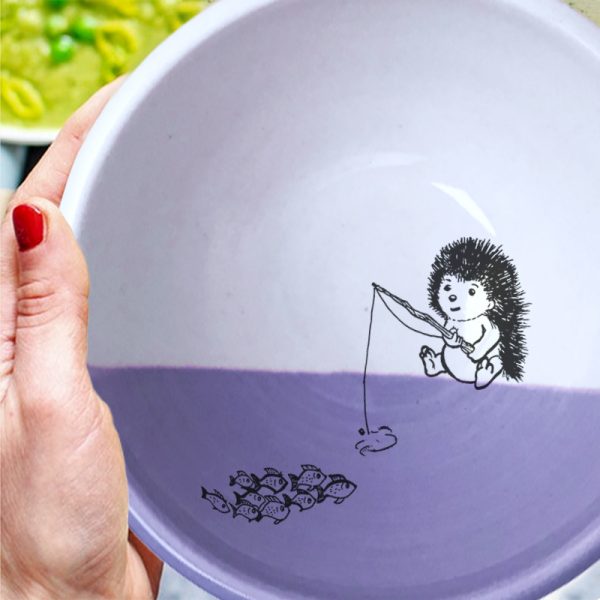 This soup bowl is for the fisherman or woman in your life. It holds fish stew, cereal or minestrone with equal panache and features a drawing of a hedgehog fishing. Lavender accent color.