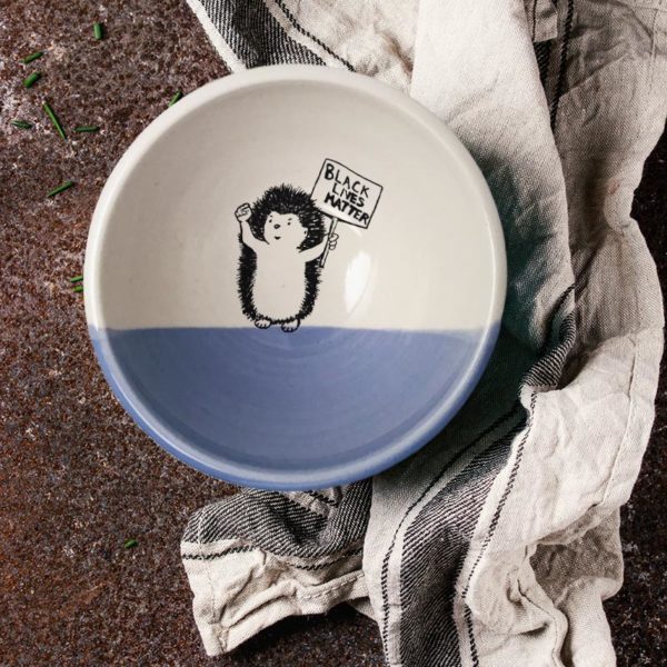 Handmade ceramic soup bowl with a drawing of a hedgehog holding a Black Lives Matter resistance sign. Lavender accent color.